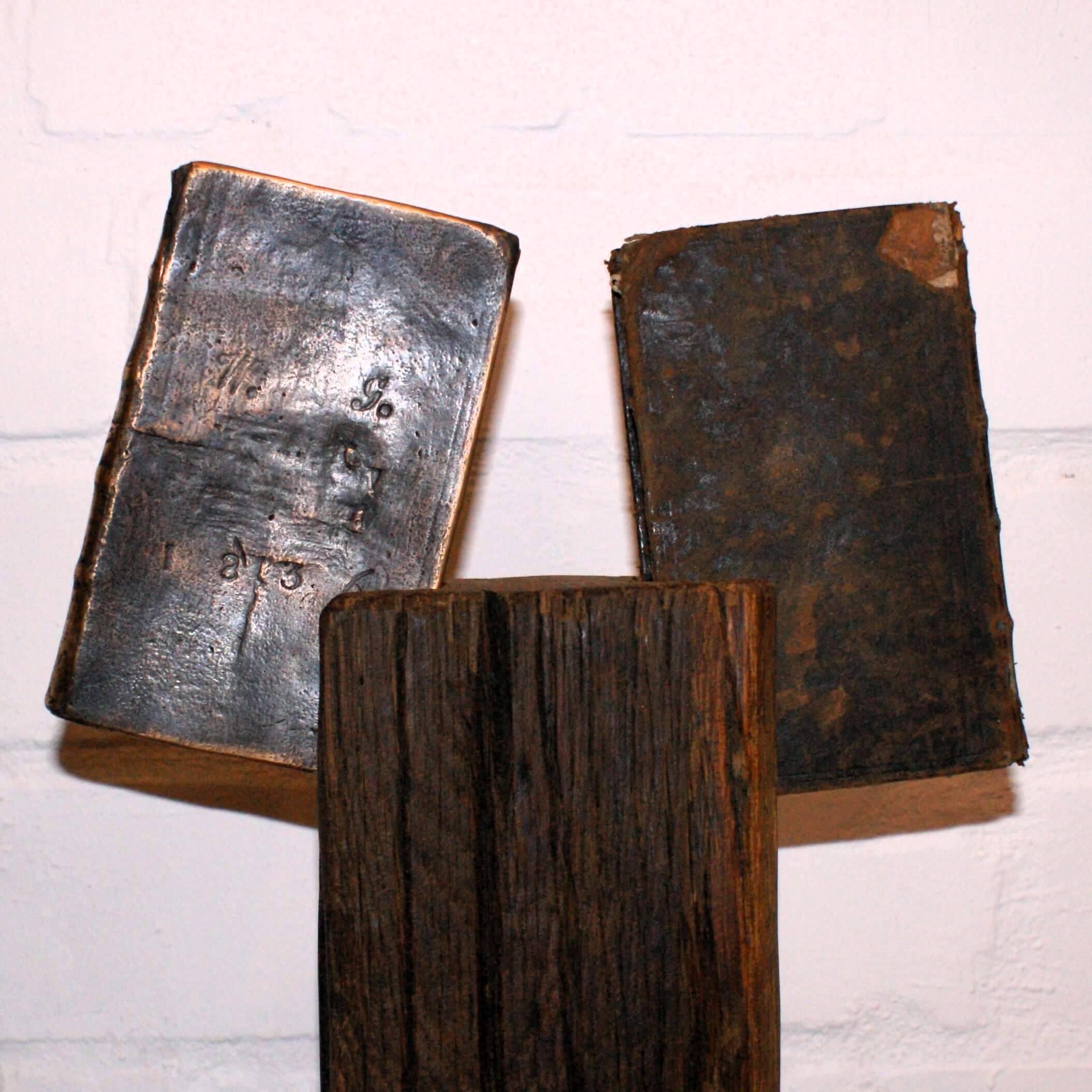 Holzfigur hält zwei Bücher aus Bronze und das Original